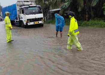 Tidak Mengenal Hujan Personel Polsek Perdagangan Pengamanan di Jalan Rusak Penuh dengan Genangan Air