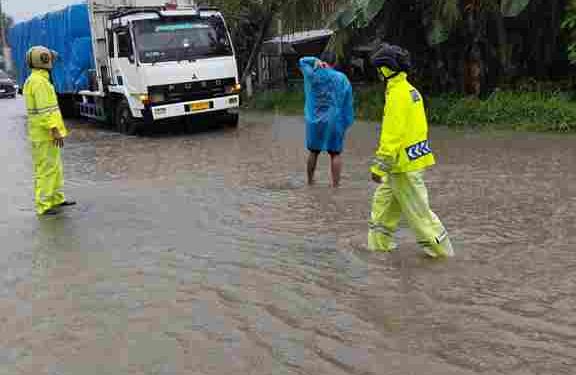 Tidak Mengenal Hujan Personel Polsek Perdagangan Pengamanan di Jalan Rusak Penuh dengan Genangan Air